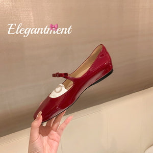 Red patent bow Mary Jane ballet flat held in hand