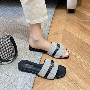 Gray double-buckle slide sandals worn indoors