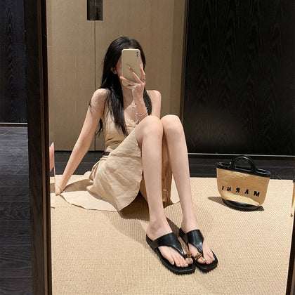 Black gold buckle toe-post sandals styled with a neutral dress