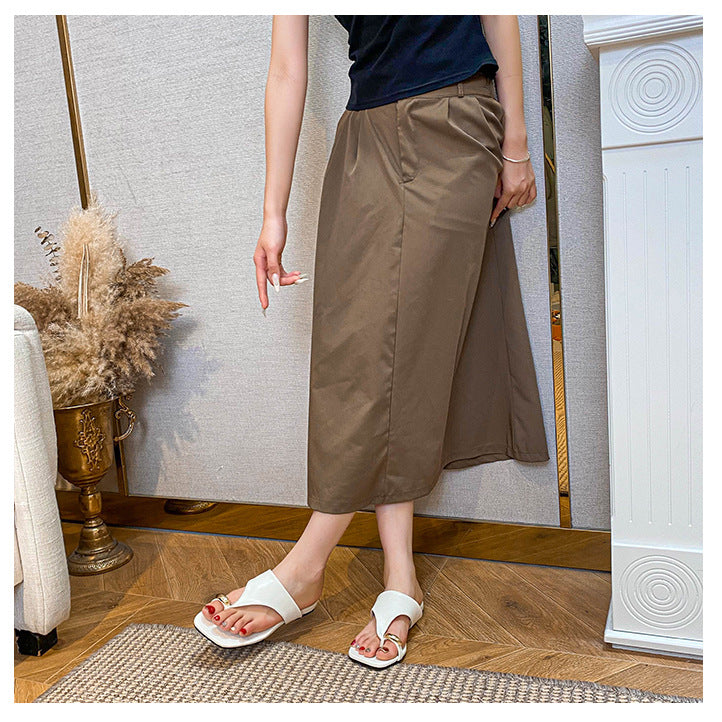 White toe-post flat sandals worn with a brown skirt
