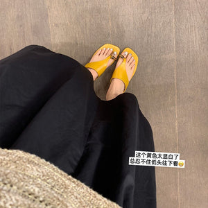Yellow gold buckle toe-post sandals worn with a black outfit