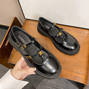 Black T-strap platform loafers held in hand