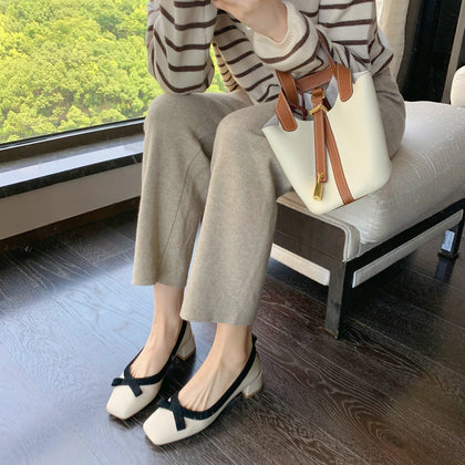 Apricot bow block heel pumps worn by a window
