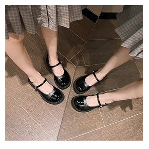 Black patent cap-toe Mary Jane pumps worn