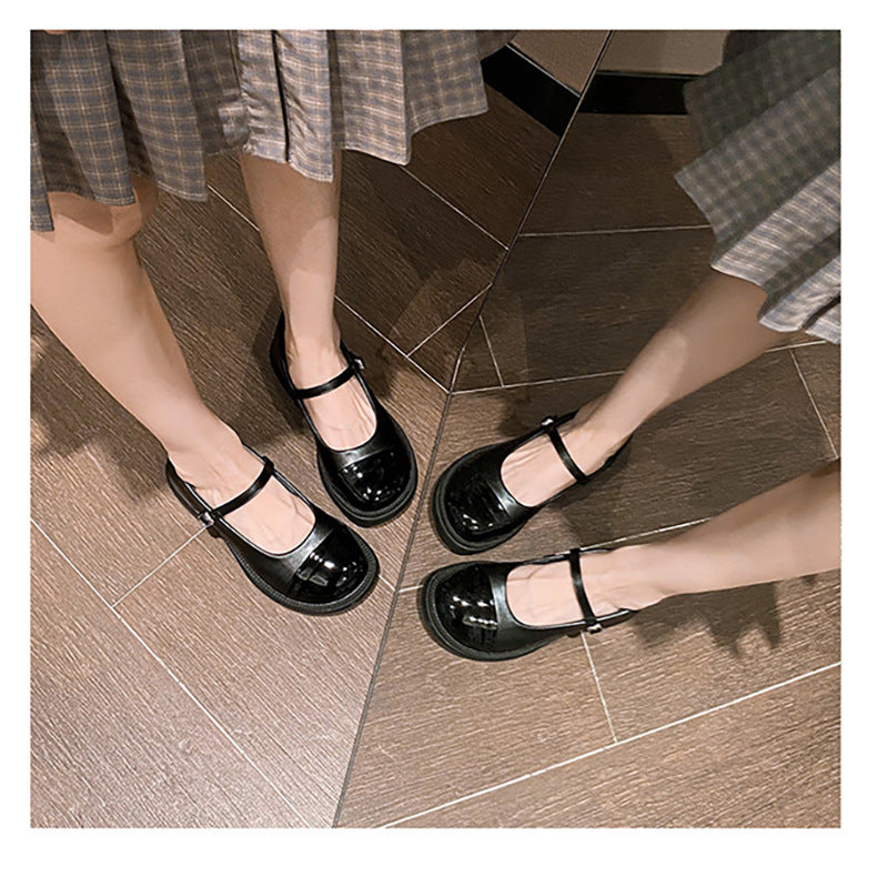 Black patent cap-toe Mary Jane pumps worn