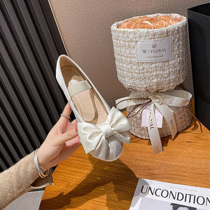 White oversized bow Mary Jane ballet flat held in hand