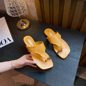 Yellow square-toe toe-post sandal pair held in hand